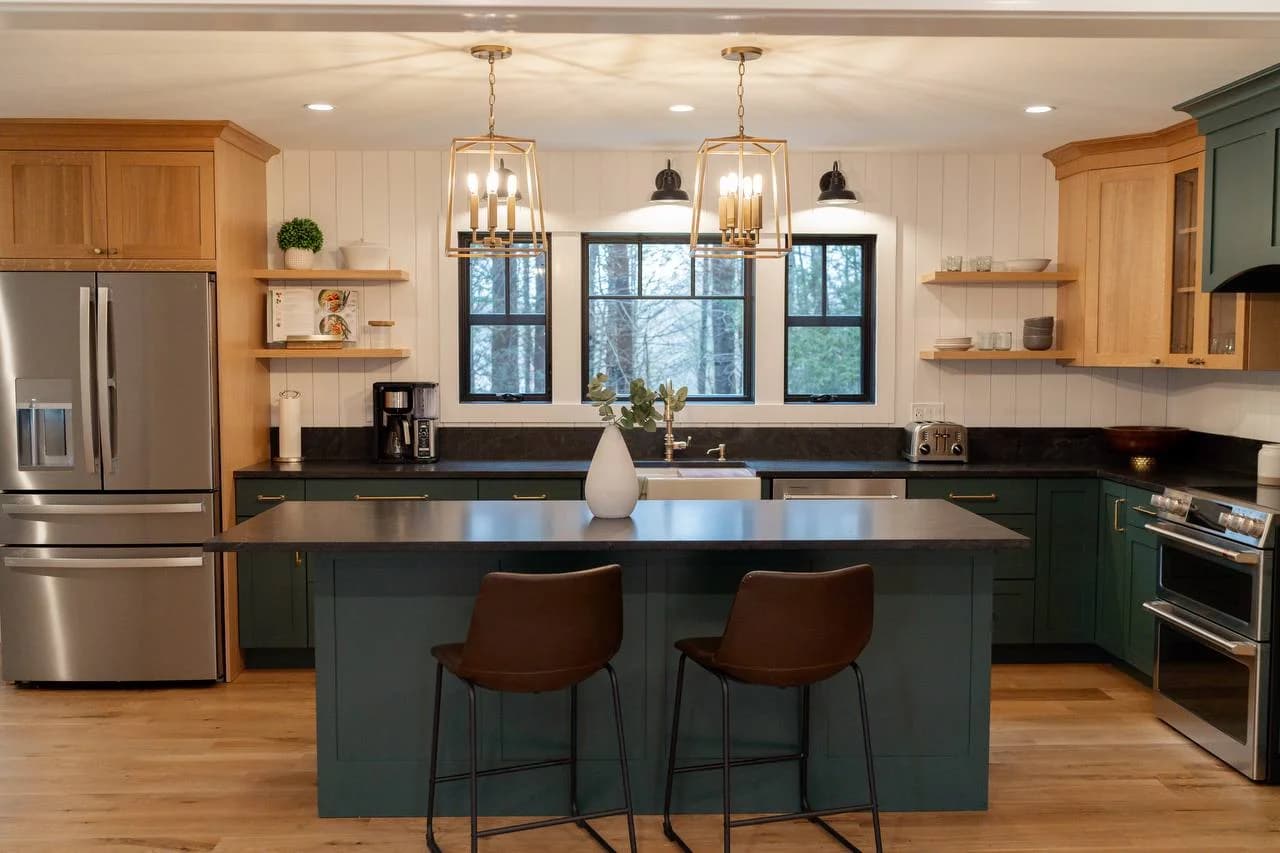 Custom kitchen with forest green cabinetry, natural wood uppers, and brass pendant lighting