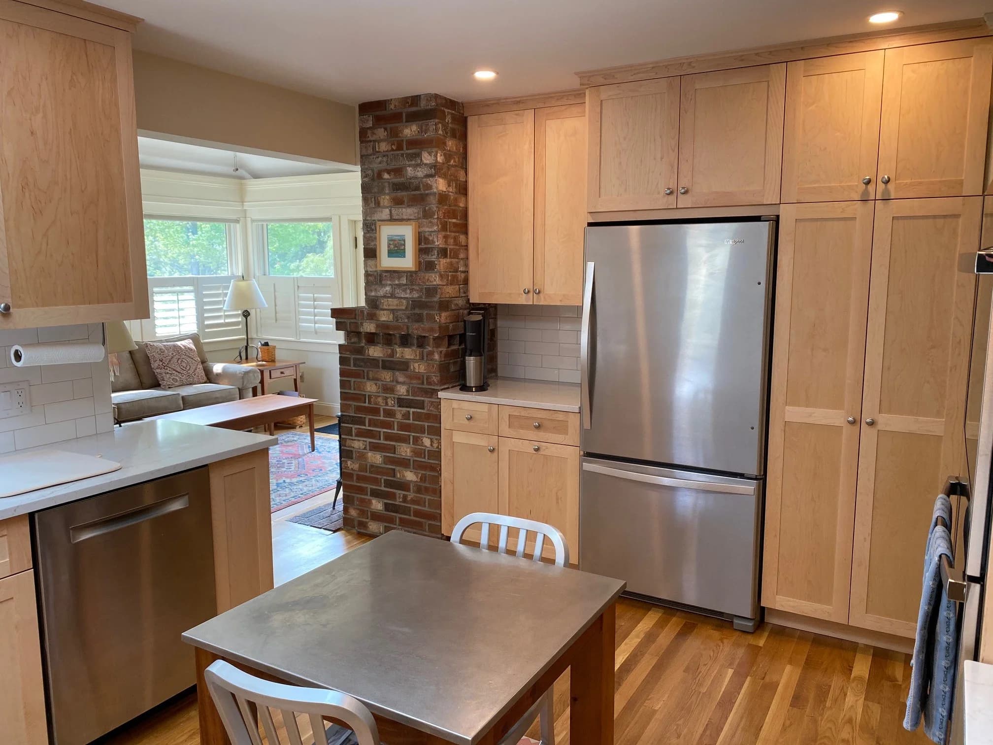 Eliot ME kitchen — natural maple shaker cabinets, white quartz counters, stainless appliances, brick chimney column