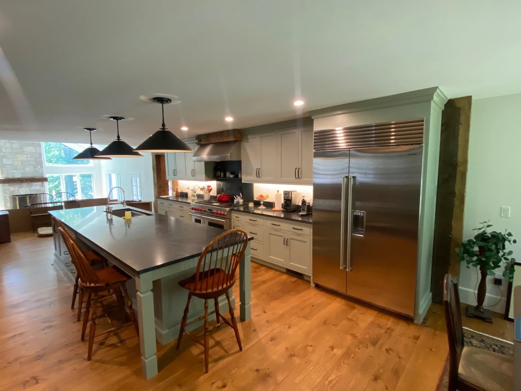 Exeter NH kitchen — sage green shaker cabinets, black stone island, Wolf range with reclaimed wood hood