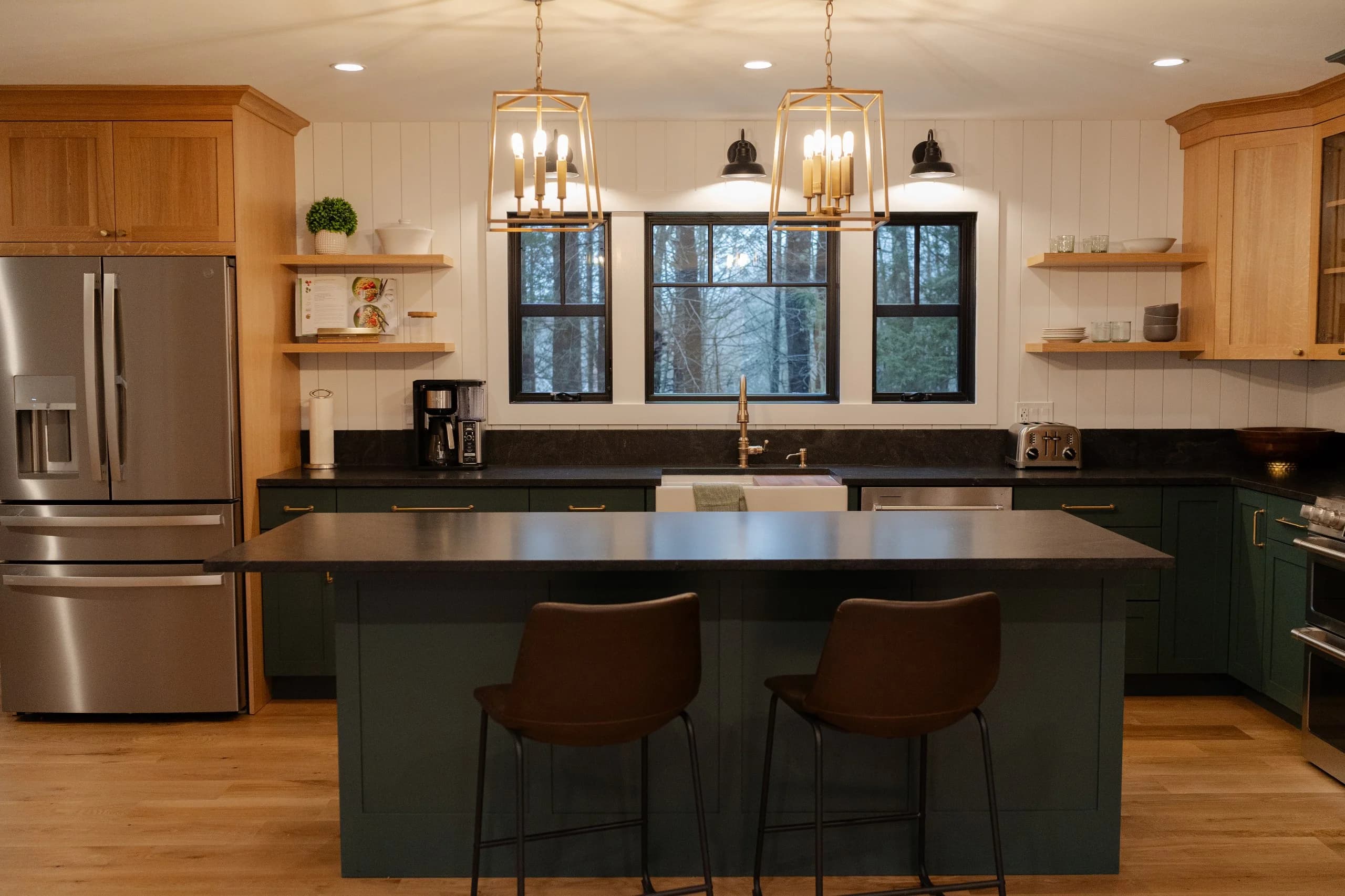 North Hampton NH kitchen — forest green and natural oak two-tone cabinets, black stone island, brass pendant lights